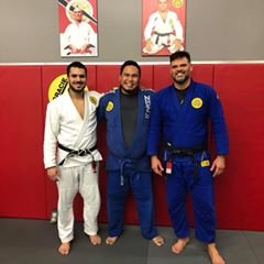Three men in Brazilian Jiu-Jitsu gis posing together in a martial arts gym.